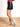 Model is wearing a black faux leather mini skirt with side slit.